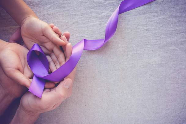 Hands holding Purple ribbons, toning copy space background, Alzheimer disease, Pancreatic cancer, Epilepsy awareness, domestic violence wareness  - Zdjęcie, obraz