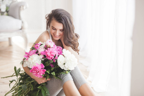 Fiatal, vonzó nő, rózsaszín és fehér bazsarózsa virágok - Fotó, kép