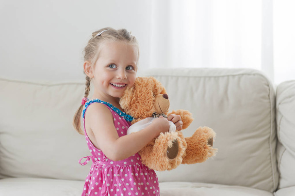 Happy toddler girl playing with her teddy bear - Фото, изображение