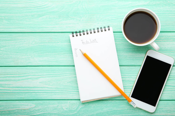 To do list in notepad with smartphone and cup of coffee on wooden table - 写真・画像