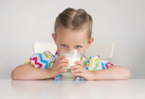dziewczynka z szklankę mleka na jasnym tle - Zdjęcie, obraz