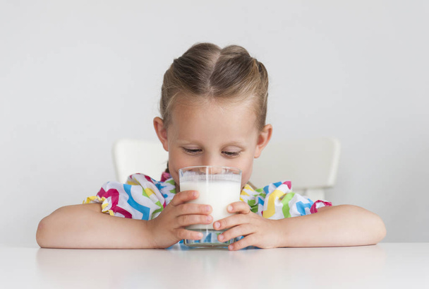 menina com copo de leite no fundo claro
 - Foto, Imagem