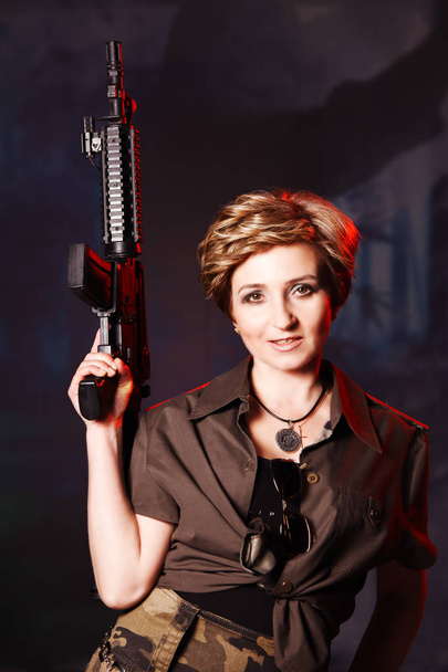 Portrait of attractive woman in military style holding gun in hands - Foto, Imagem