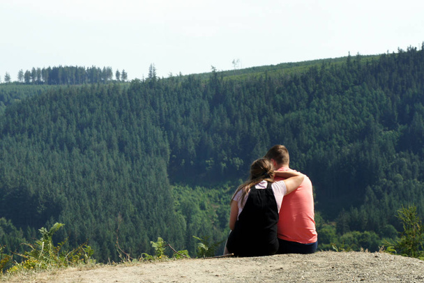 A pair of young people sitting over a mountain valley. - Photo, Image
