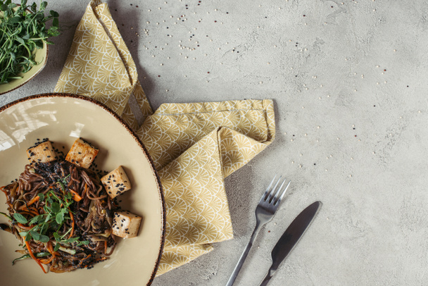 composição de alimentos com soba com tofu e legumes decorados com sementes germinadas de girassol em mesa cinza
 - Foto, Imagem