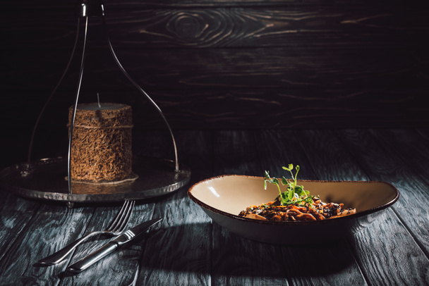 composición alimenticia de vela, tenedor con cuchillo, soba con tofu y verduras decoradas con semillas germinadas de girasol
 - Foto, imagen