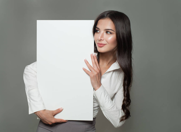 Jeune femme d'affaires tenant fond de bannière en papier blanc blanc avec espace de copie pour la publicité. Succès commercial, marketing publicitaire ou concept éducatif
 - Photo, image