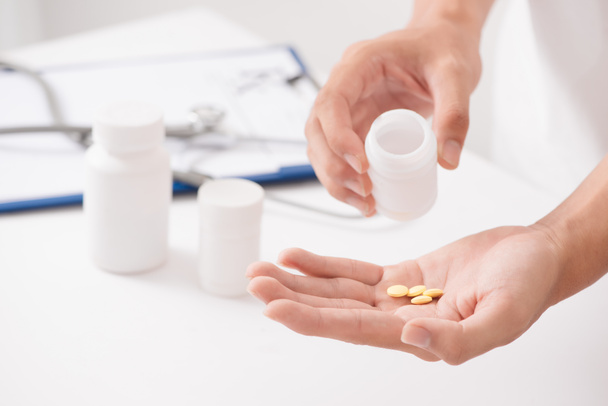 Close-up op vrouwelijke handen met de pillen en verpakking geïsoleerd op witte achtergrond. - Foto, afbeelding