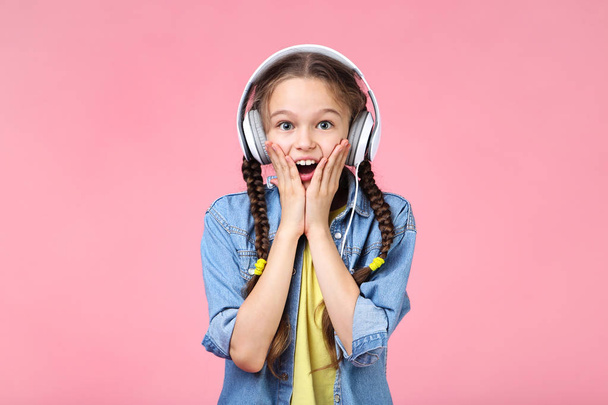 Young girl with headphones on pink background - Foto, imagen