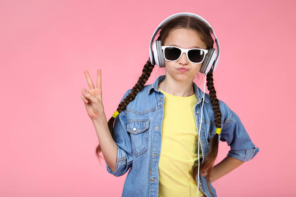 Young girl with headphones on pink background - Photo, Image