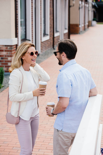 sonriente pareja de pie con tazas de café desechables en la calle
 - Foto, imagen