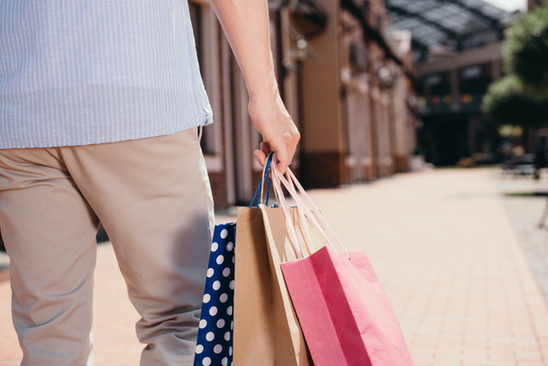 cropped image of man walking with shopping bags on street - Foto, Bild
