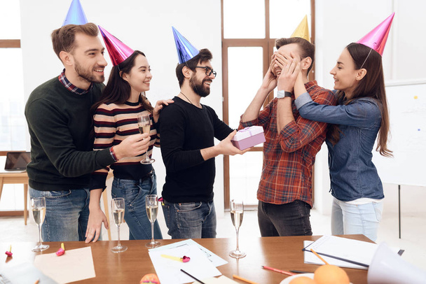 Colleagues surprise another employee of the company. They have caps on their heads. They are in a good mood. - Foto, Bild