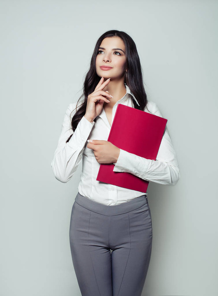 Business woman with red folder looking up and smiling, portrait  - Fotografie, Obrázek