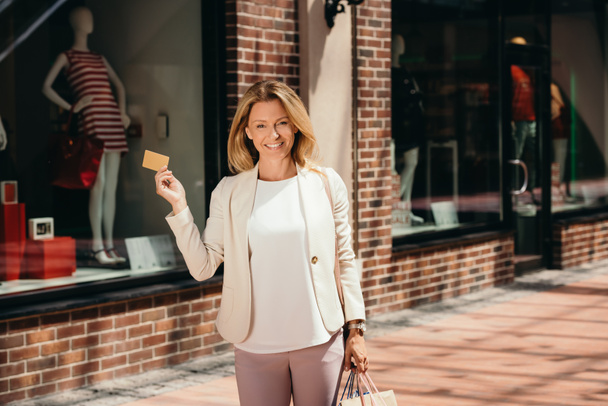 attractive woman holding credit card and shopping bags on street - Photo, image