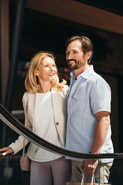 pareja sonriente en la escalera móvil en el centro comercial
 - Foto, imagen