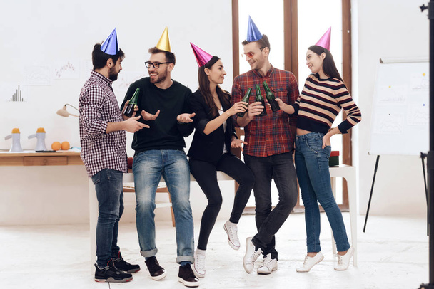 Young employees of the company celebrate a corporate holiday. They put on holiday caps and have fun. - Foto, imagen