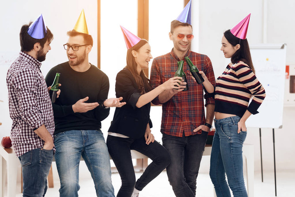 Young employees of the company celebrate a corporate holiday. They put on holiday caps and have fun. - Fotoğraf, Görsel