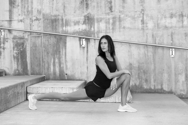 Νεαρή ελκυστική γυναίκα γυμναστικής εκτελεί ένα σπάγκο - Φωτογραφία, εικόνα