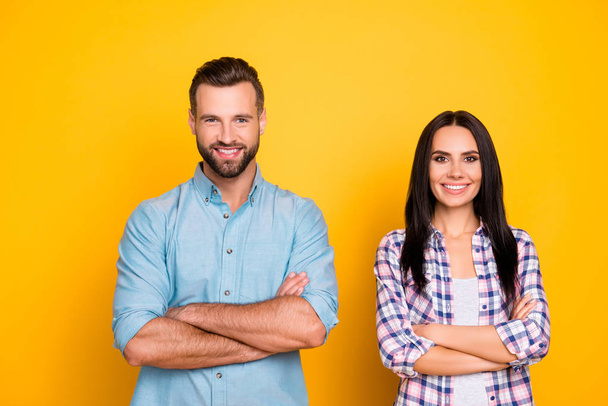 Portrait of cheerful joyful couple holding arms crossed looking at camera isolated on bright yellow background - Foto, Imagem