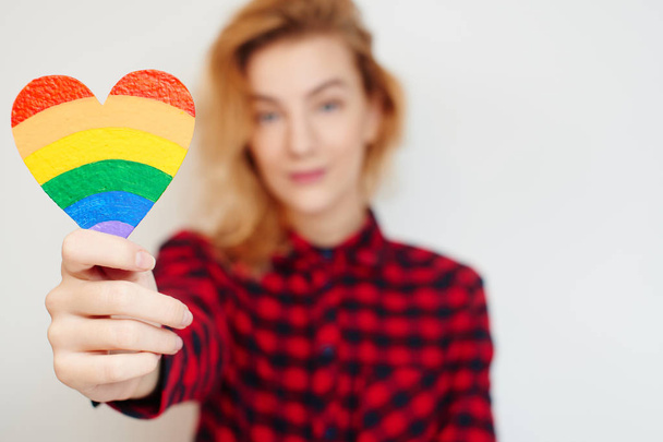 attractive woman in checkered shirt holding heart with LGBT flag in hand isolated on white background - Valokuva, kuva