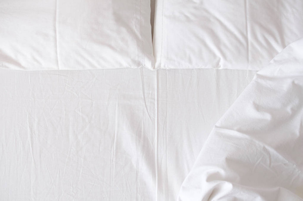 Белое постельное белье, одеяло и подушки в номере. Отдых, сон, комфорт. Вид сверху. Копирование пространства
. - Фото, изображение