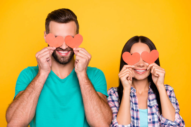 Portrait of creative joyful couple closing eyes with small paper carton red hearts isolated on vivid yellow background. Fall in love story true feelings concept - Φωτογραφία, εικόνα