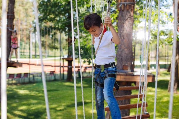 Alegre niño preadolescente disfrutando del día en el parque de cuerdas
 - Foto, imagen