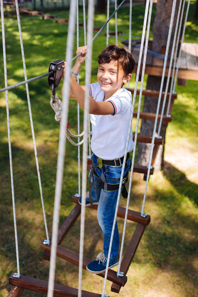 Happy preteen boy standing on swing at rope park - Foto, imagen