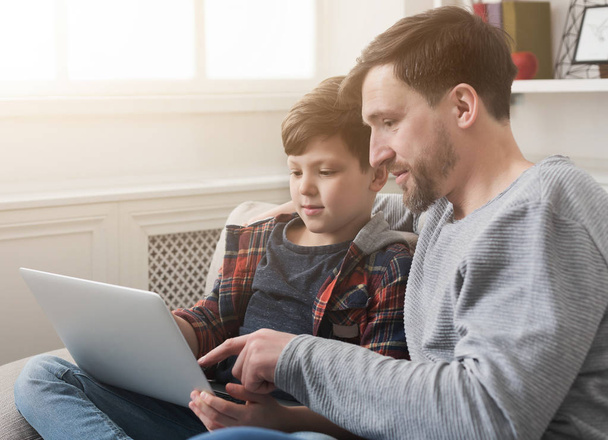 Pai e filho felizes usando laptop em casa
 - Foto, Imagem
