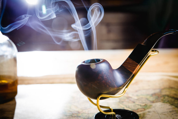 Smoking pipe on a wooden table - Fotoğraf, Görsel