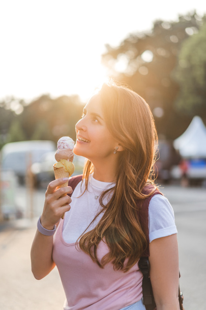 side view of smiling young woman eating ice cream  - Valokuva, kuva