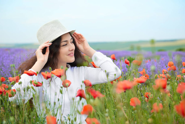 young girl is in the lavender field with red poppy flowers, beautiful summer landscape - Photo, Image