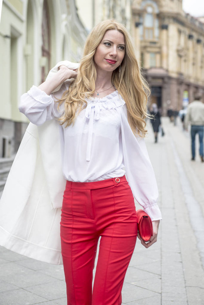 Fashionable young blonde in a spring fashionable suit and with a shopping bag in the center of Moscow - Valokuva, kuva