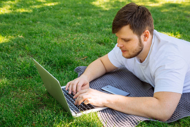 yaz günü şehir parkı içinde laptop üzerinde genç yetişkin adam - Fotoğraf, Görsel