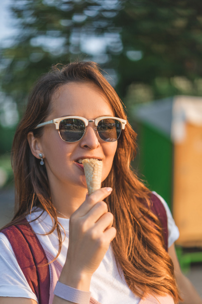 mosolygó fiatal nő eszik fagylaltot napszemüveg - Fotó, kép