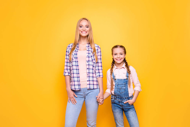 Portrait of beautiful cheerful glad nice two with toothy smile sisters. Sweet adorable lovely girlish kid with pigtail older sister wearing casual denim outfit isolated on bright vivid background - Zdjęcie, obraz