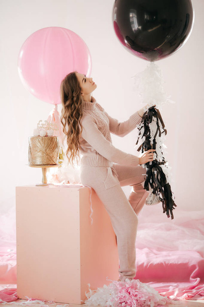Portrait of beautiful young woman with makeup in stylish  dress posing in studio with balloons on background  - Photo, Image