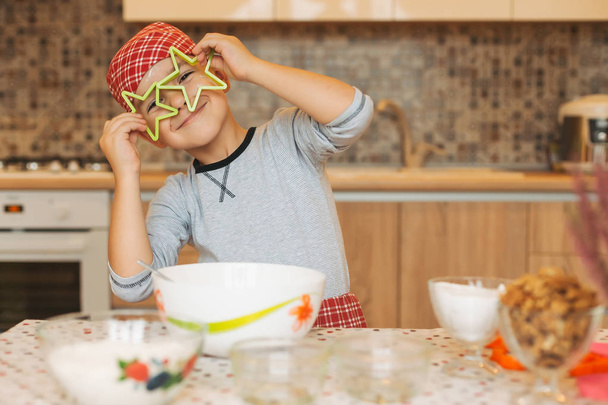 Funny boy having fun at home, holds cookies forms stars before h - Photo, Image