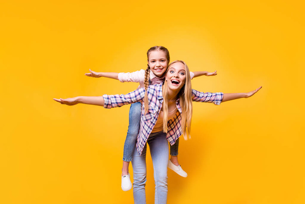 Parenthood siblings game checkered shirt stylish modern outfit concept. Excited cheerful cute funky carefree pretty mum carrying on back kid making airplane winds isolated on bright background - Photo, image