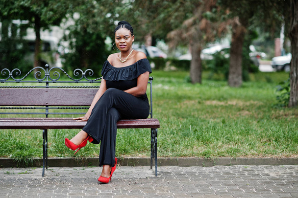 African girl posed at street of city wear on black, sitting on the bench. - Foto, Imagem