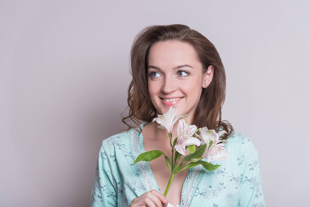 Woman with a flower. Woman on white background. A girl is holding flowers in her hands on a white background. - Фото, зображення