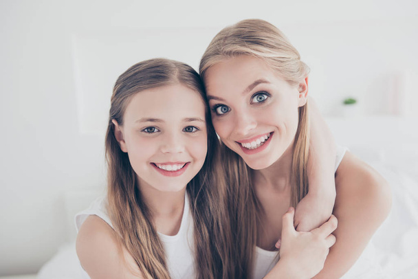 Close up portrait family photo of cute sweet lovely beautiful charming glad cheerful with toothy beaming smile mum and her pretty daughter embracing neck spending time together domestic life - Photo, image