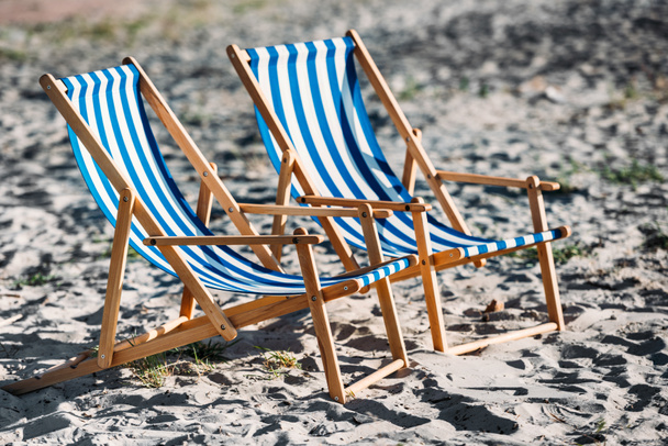 striped beach chairs and cooler on sandy coast - 写真・画像