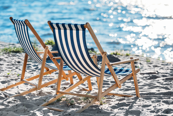 chaises longues rayées et plus fraîches sur la plage de sable fin
 - Photo, image