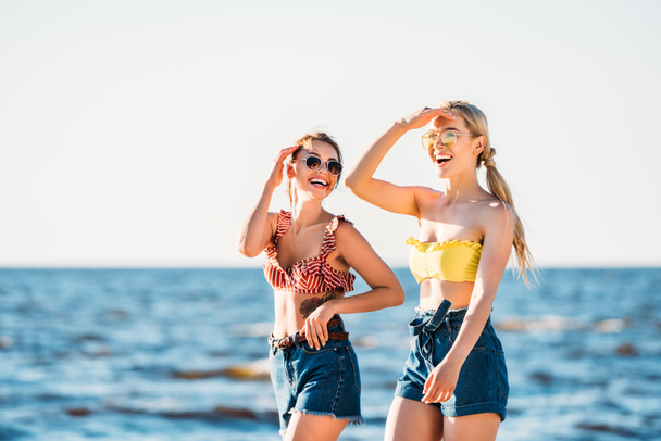 jeunes femmes heureuses en lunettes de soleil marchant ensemble sur la plage
 - Photo, image