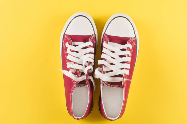New red sneakers on yellow background with copy space. Top view. Retro fashion concept - Valokuva, kuva