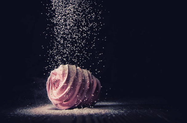 Сахарный рулет падает на зефир на темном фоне, макрос
 - Фото, изображение