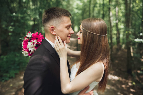 Beautiful young wedding couple is kissing and smiling in the park - Fotoğraf, Görsel
