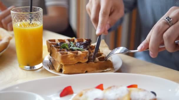 Чоловічі руки вирізають смачні бельгійські вафлі ножем і виделкою в ресторані
 - Кадри, відео